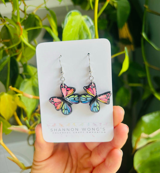 Butterfly earrings held in hand for scale