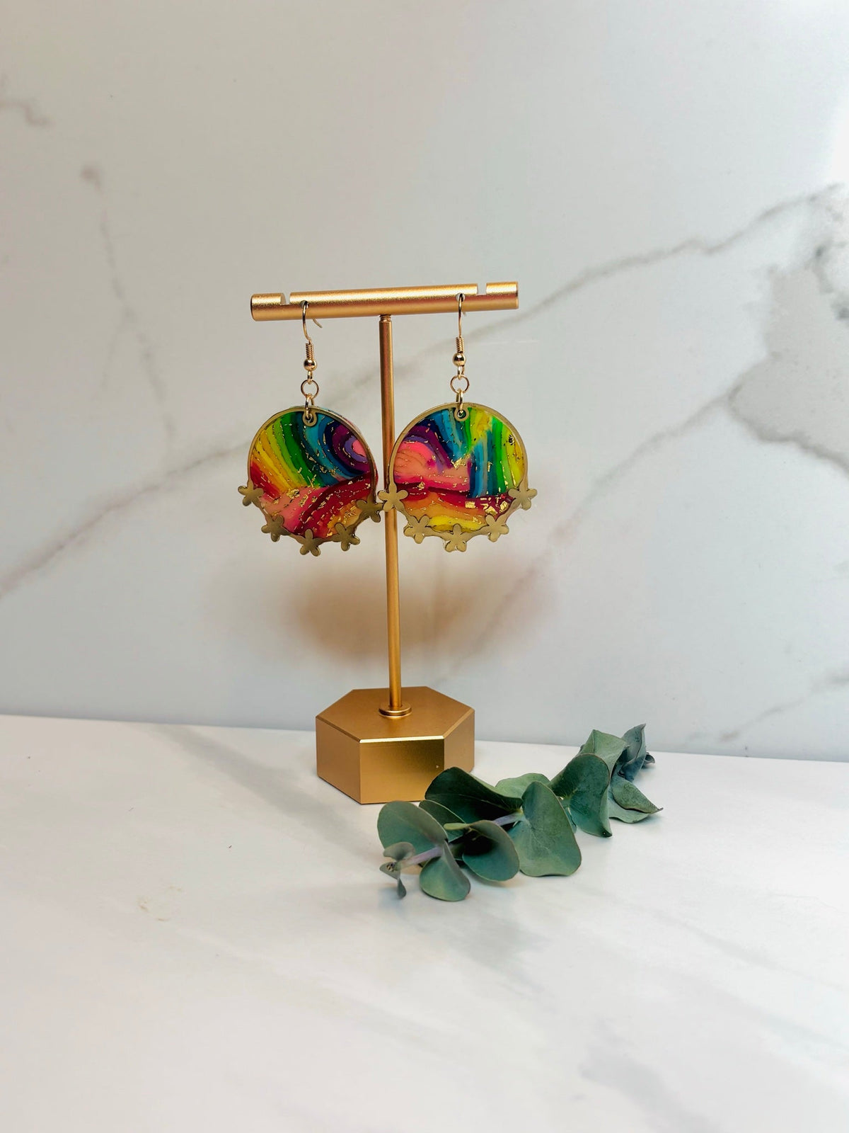 Rainbow bezel earrings on a gold display stand